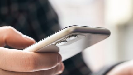 A man holds a smartphone and works at a laptop, the concept of working in the office, technology at work.